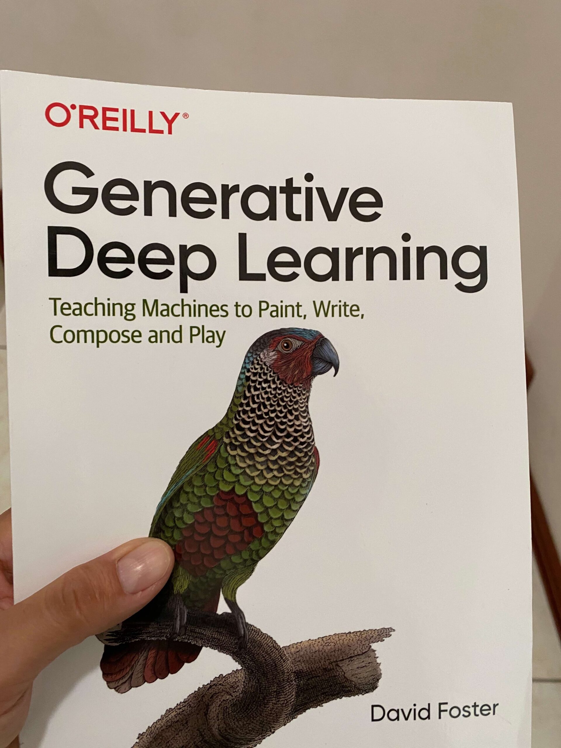 Photo of a technical book named Generative Deep Learning, it has a colorful parrot with greens and reds in the cover over a white background